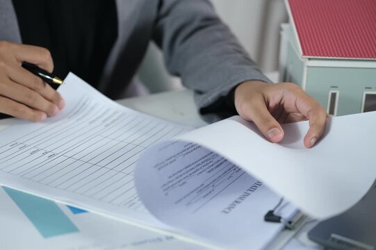 A beautiful property agent opens and checks real estate insurance documents to ensure the validity of the agreement or contract.