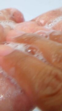 Close up of palm of hand filled with rich foam from soap, shampoo, and beauty serum. Detailed bubbles and wet skin texture on clean white background. Skincare and cleansing concept.