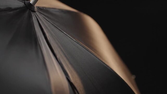 A close up view of a black umbrella fabric against a dark background