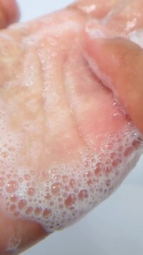 Rubbing foam bubbles on hand. Shampoo foam and beauty gel serum foam. Close up view of bubbles on palm. Skincare and haircare concept, cleansing texture.