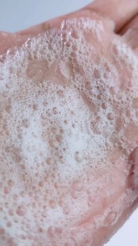 Spreading soap foam bubbles on palm and showing it from close up. Hand hygiene concept, cleansing bubbles for daily skincare routine.