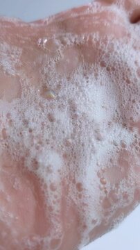 Close up view of palm of hand filled with rich cleansing soap foam. Detailed shot showing wet skin texture and abundant delicate bubbles. Hand cleansing concept.