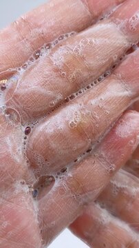 Palm full of soap. Close up of soap foam spreading on hand. Cleansing bubbles, hand hygiene concept for daily skincare routine.