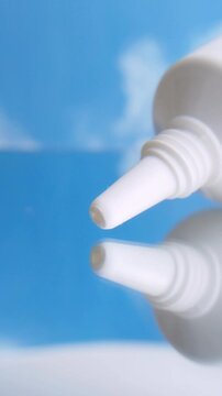 White beauty cream being dispensed from product packaging onto reflective glass surface. Close up view of thick white cream texture flowing out with clear reflection on glass.