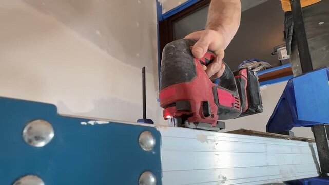 A close-up of the process of cutting materials with a jigsaw. A craftsman cuts construction materials.