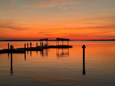 Sunset over lake dock pier dramatic orange black silhouette