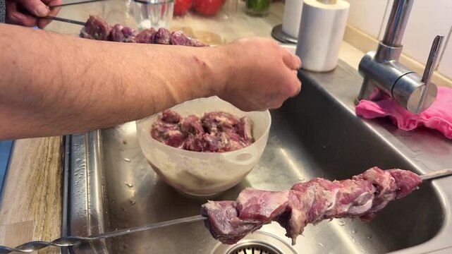 Man Threading Marinated Lamb Meat onto Skewers for Barbecue.
