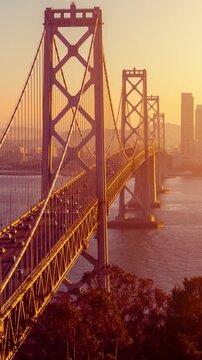 Traffic driving across the Bay Bridge towards downtown San Francisco at sunset. Vertical Video.