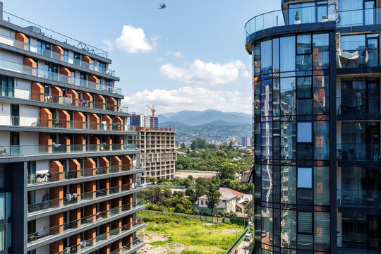 BATUMI, GEORGIA &mdash; AUGUST 13, 2025: Modern skyscraper architecture and real estate development against the Caucasus mountains.