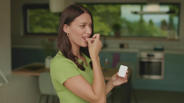 Young woman taking vitamin B pill from container at home kitchen, 4K slow motion
