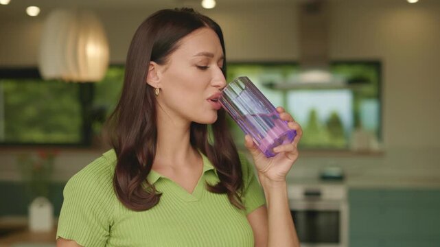 Young woman taking clear vitamin capsule at home kitchen, 4K slow motion