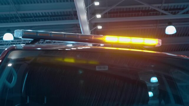 A flashing yellow light flashes on the red roof of an SUV at an exhibition. Shot in motion