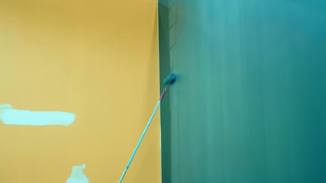 A long-handled roller is used to paint the high wall of the pavilion blue before an upcoming public event 