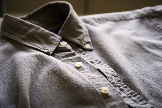 Close-up view of a gray button-down shirt laid flat with focus on the collar, buttons, and textured fabric.Casual fashion, clothing design, everyday apparel. Simplicity, comfort, minimalist wardrobe