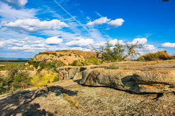 Rugged granite ledges overlook the vast green horizon and distant domes under a vibrant cloudy sky at Enchanted Rock. © ZL Visuals