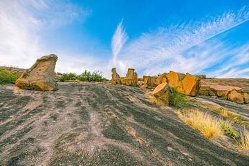 Unique weathered granite rock formations stand against a dramatic blue sky on the smooth summit trail at Enchanted Rock © ZL Visuals