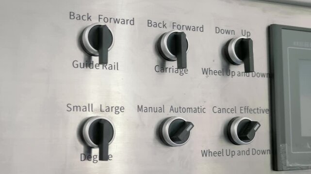 On the stainless steel panel there are rows of switches for industrial equipment operation modes. Closeup. Shot in motion