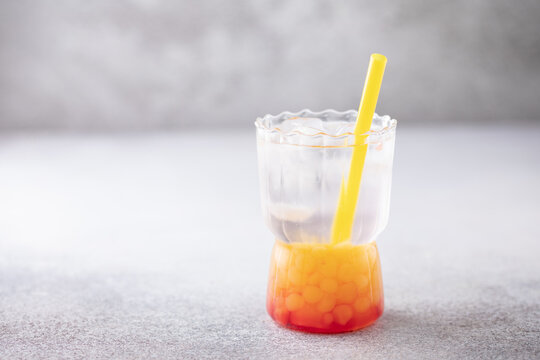 Glass of homemade fruit lemonade with popping boba or bubble pearls. Trendy summer drink