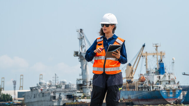 Professional woman in safety uniform monitoring global trade and shipping cargo operations.
