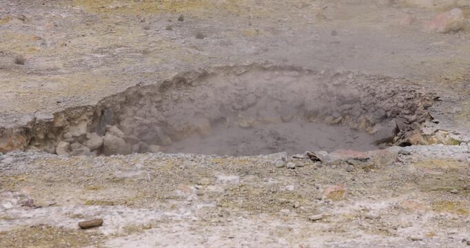 Volcanic pit with mud and boiling water with steam rising to the surface in a pond at Furnas, Azores.