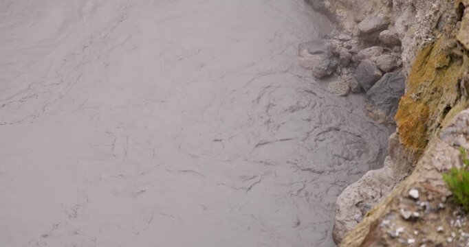 Volcanic pit with mud and boiling water with steam rising to the surface in a pond at Furnas, Azores.