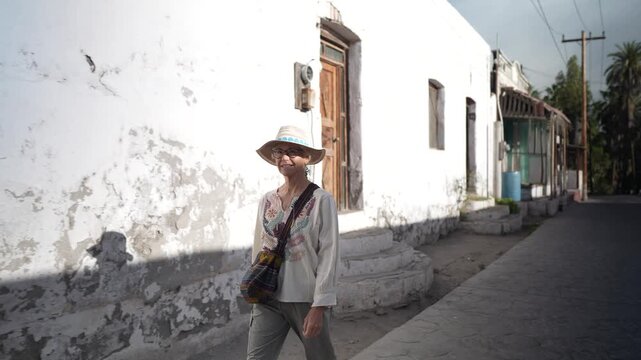 Mature woman explores the streets of San Ignacio, Baja California Sur, looking at the mission church and local architecture.