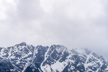 Obraz premium Jagged snow covered mountain peaks beneath storm clouds in British Columbia