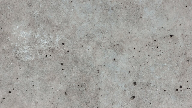 Gray pitted concrete wall texture with pockmarks and weathered patches for a grunge background