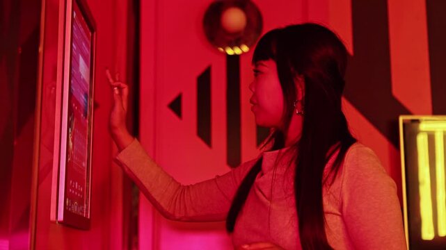 Asian woman choosing a song and dancing in a private karaoke room