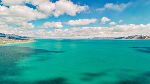 Drone view of turquoise Bear Lake with cloud shadows and distant mountains in Utah USA