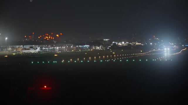 A commercial aircraft lifts off the runway at night shot with a tilt-shift lens, selective focus creating a dreamy miniature effect with vivid green, amber and orange bokeh runway lights stretching