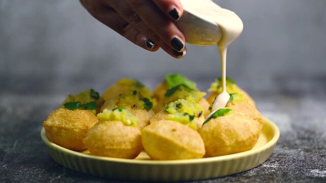 Close up of Indian street food fuchka on a plate glass with sour spicy water. Dahi Pani puri a chat item in India. 4K indian street food snacks.