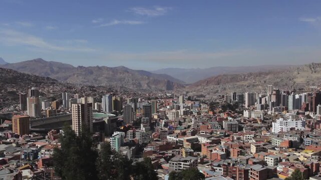 Horizontal pan of the city of La Paz, Bolivia, viewing the city center. It is a sunny day, the city is seen between mountains, with buildings, houses, and the Hernando Siles Stadium.