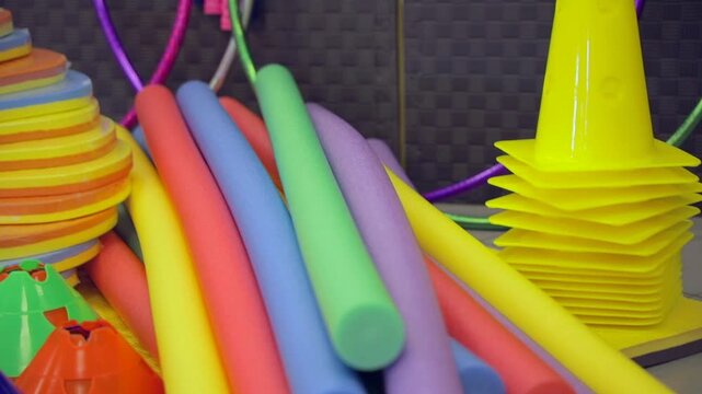 Foam tubes, cones, and other sports equipment stacked in an orderly manner. Colorful and well-organized sports material.
