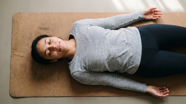 Woman lying on yoga mat in relaxed meditation pose for wellness