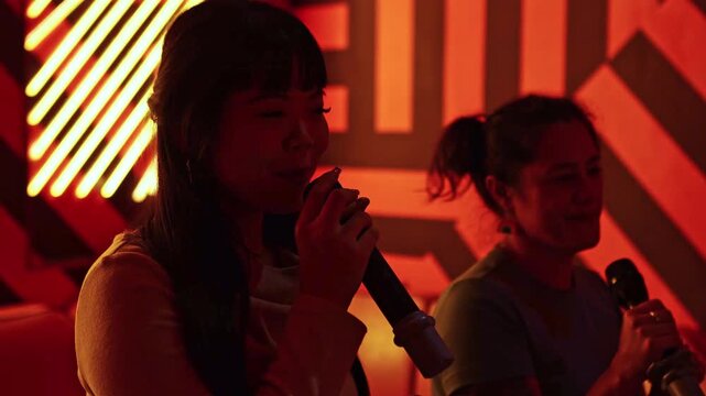 Two asian friends singing together at a karaoke party