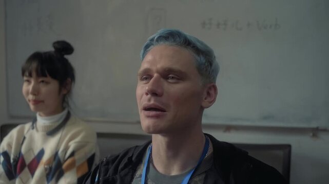 Young man with blue hair studying a foreign language with an asian female classmate