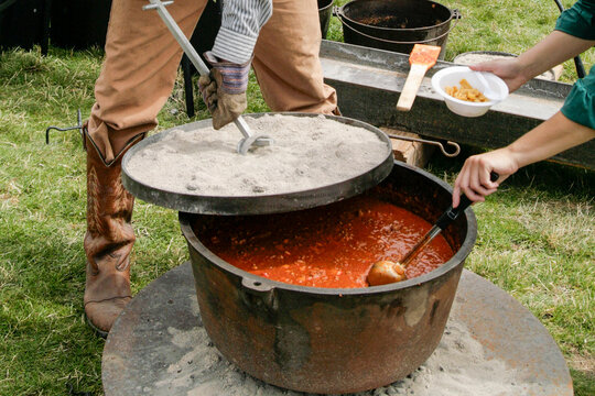Large pot of chili being cooked on an open fire outdoors