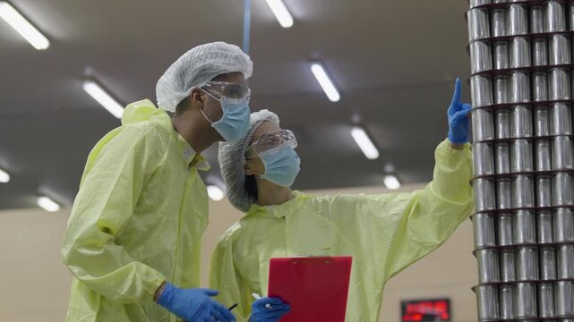 Food factory automated production line, cleanroom worker safety inspector protective suit, face mask, gloves, hair net, examining metal containers laboratory and factory inspection process