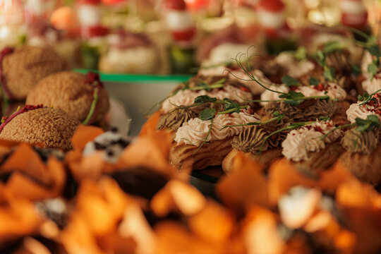 A wide selection of savory eclairs and sweet choux pastries are artfully arranged for a professional banquet. The image showcases the diversity of a high-end hospitality menu.