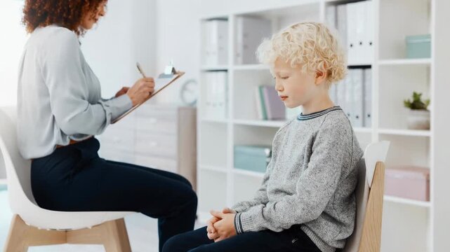 Young boy sitting quietly during psychological evaluation with caring professional in clinical setting