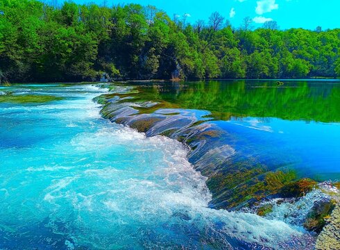 River with clean water and waterfalls in magnificent green nature with trees and blue sky