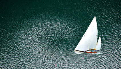 Velero navegando sobre un mar verde oscuro, donde el agua forma un remolino hipnótico. Simboliza equilibrio entre movimiento y calma, una danza entre control y caos. © Menorcaevo