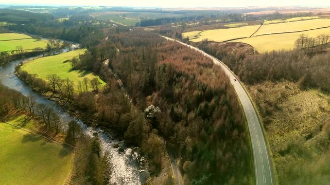 Scottish Borders UK: The River Esk winds through green fields and dense trees near Langholm in the Scottish Borders. This scene shows a clear view of the landscape on the A7