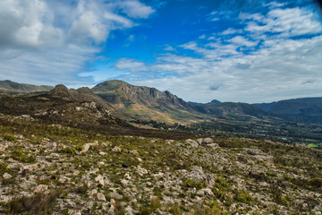Fototapeta premium A panoramic view of mountains with rocky terrain under a partly cloudy sky, showcasing natural beauty in a serene, outdoor setting.