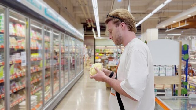 Young man shopping in supermarket, reading product information	