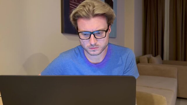 A young man works on a laptop from home