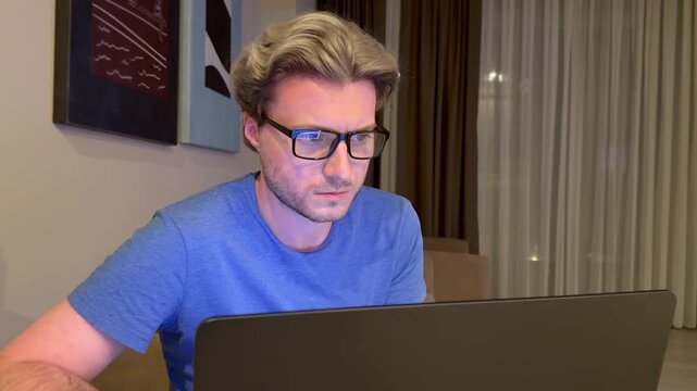 A young man works on a laptop from home