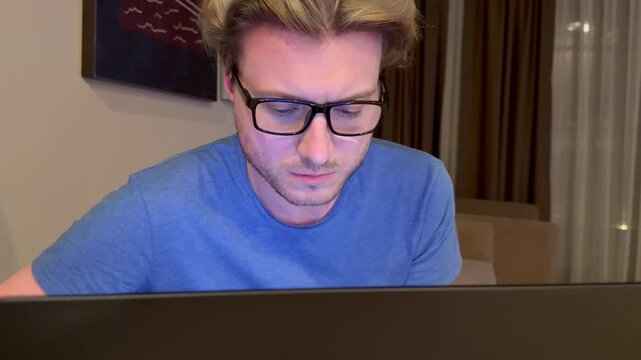 A young man works on a laptop from home