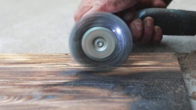 Wood brushing process with a wire wheel brush on charred timber close up